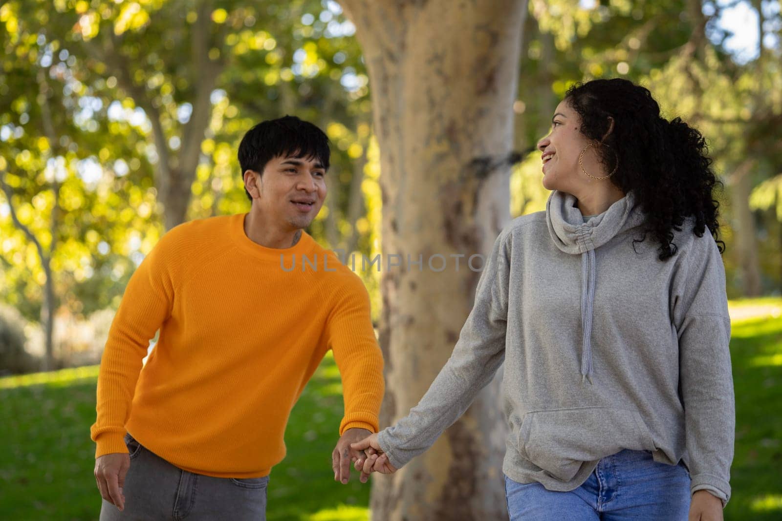 Happy woman and boyfriend holding hand in a park.Couple having fun together with love by papatonic