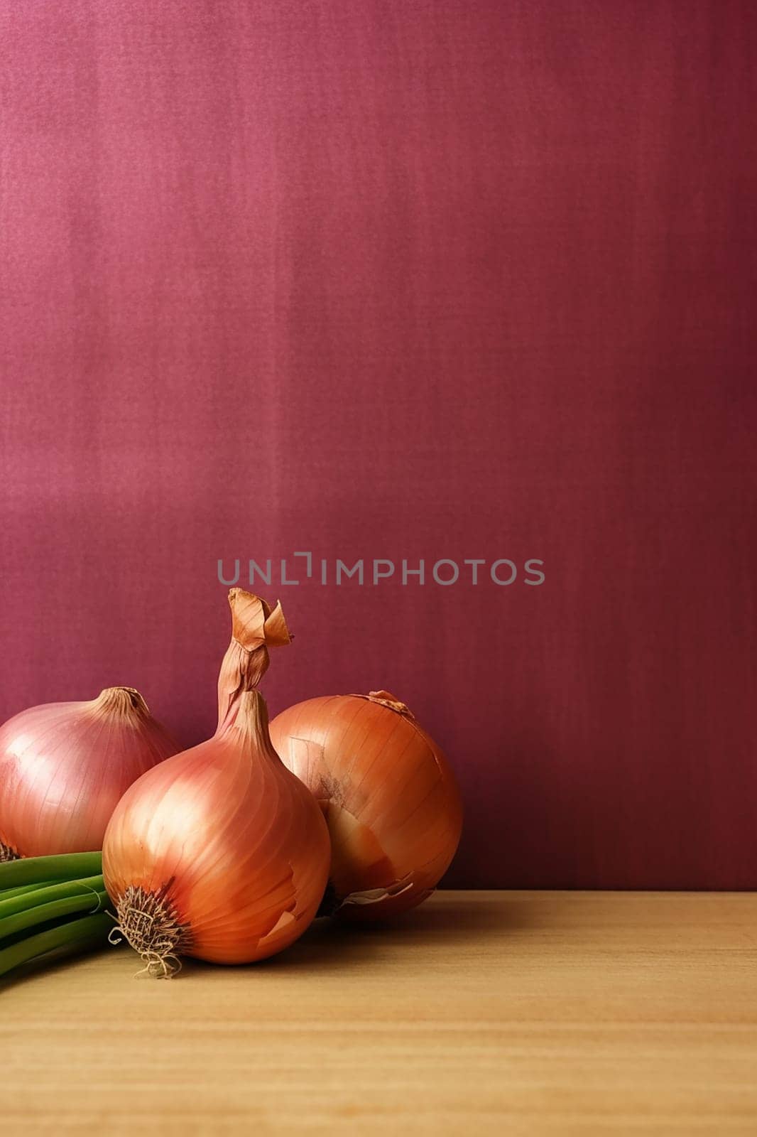 Several onions placed on a wooden surface against a maroon background.