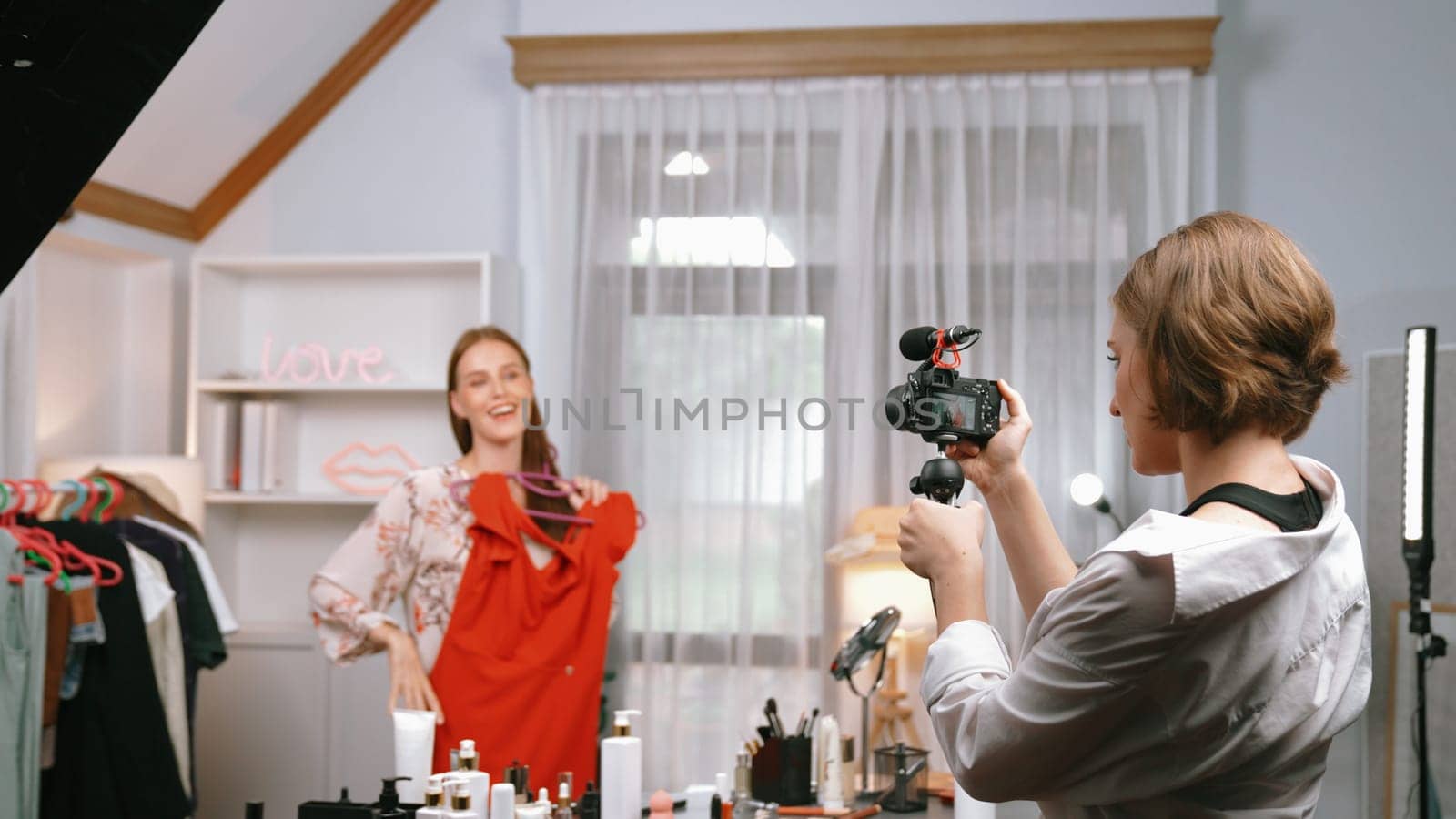 Two women influencer shoot live streaming vlog video review clothes prim social media or blog. Happy young girl with apparel studio lighting for marketing recording session broadcasting online.