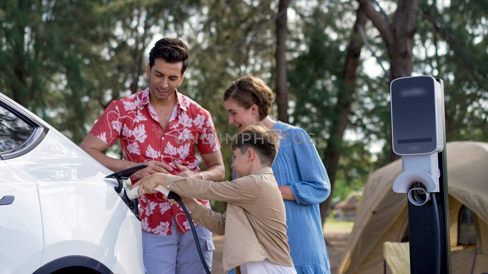 Lovely family recharge EV car with EV charging station in campsite. Perpetual by biancoblue