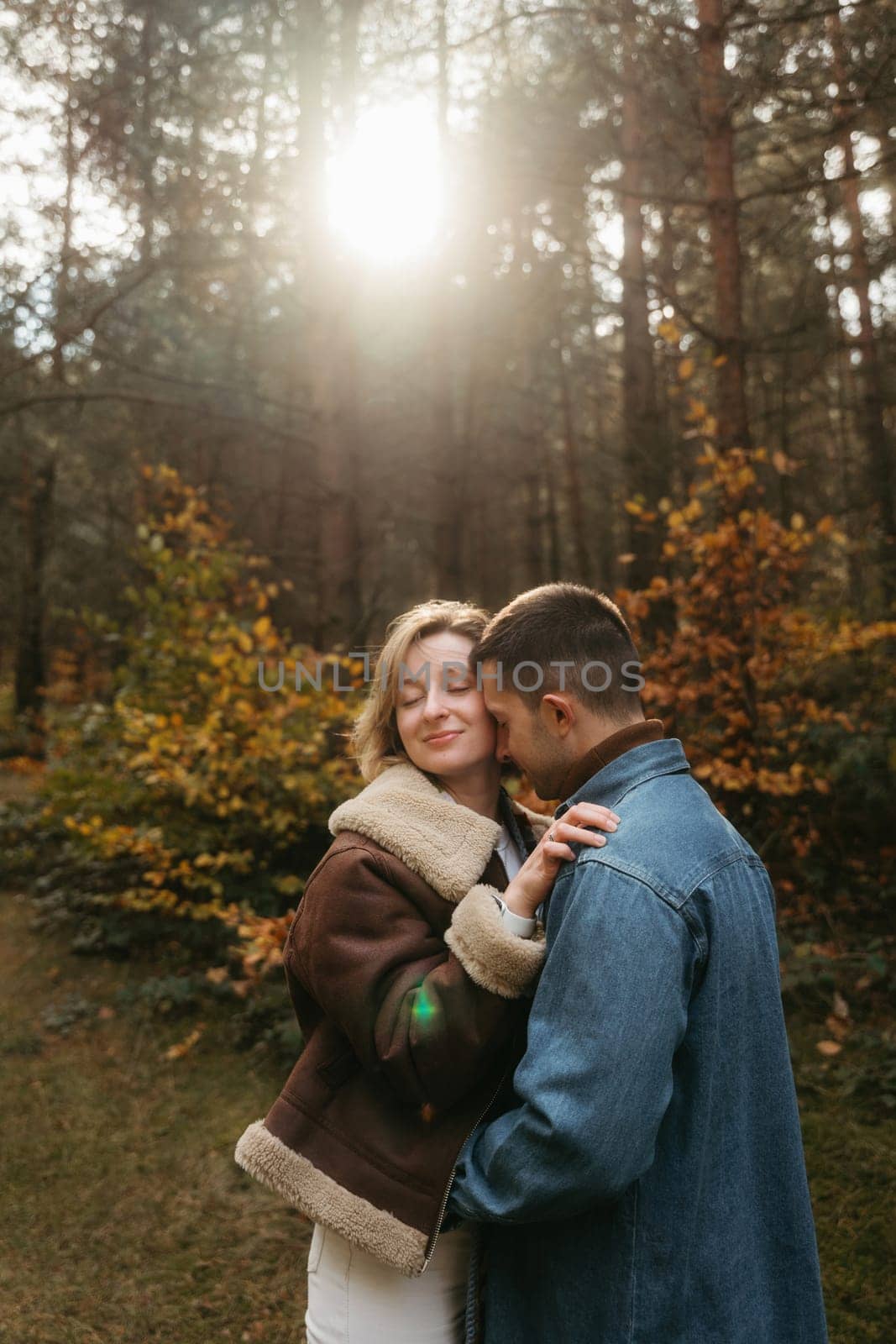 A man and a woman are hugging in the woods with sunlight on the background by Romvy