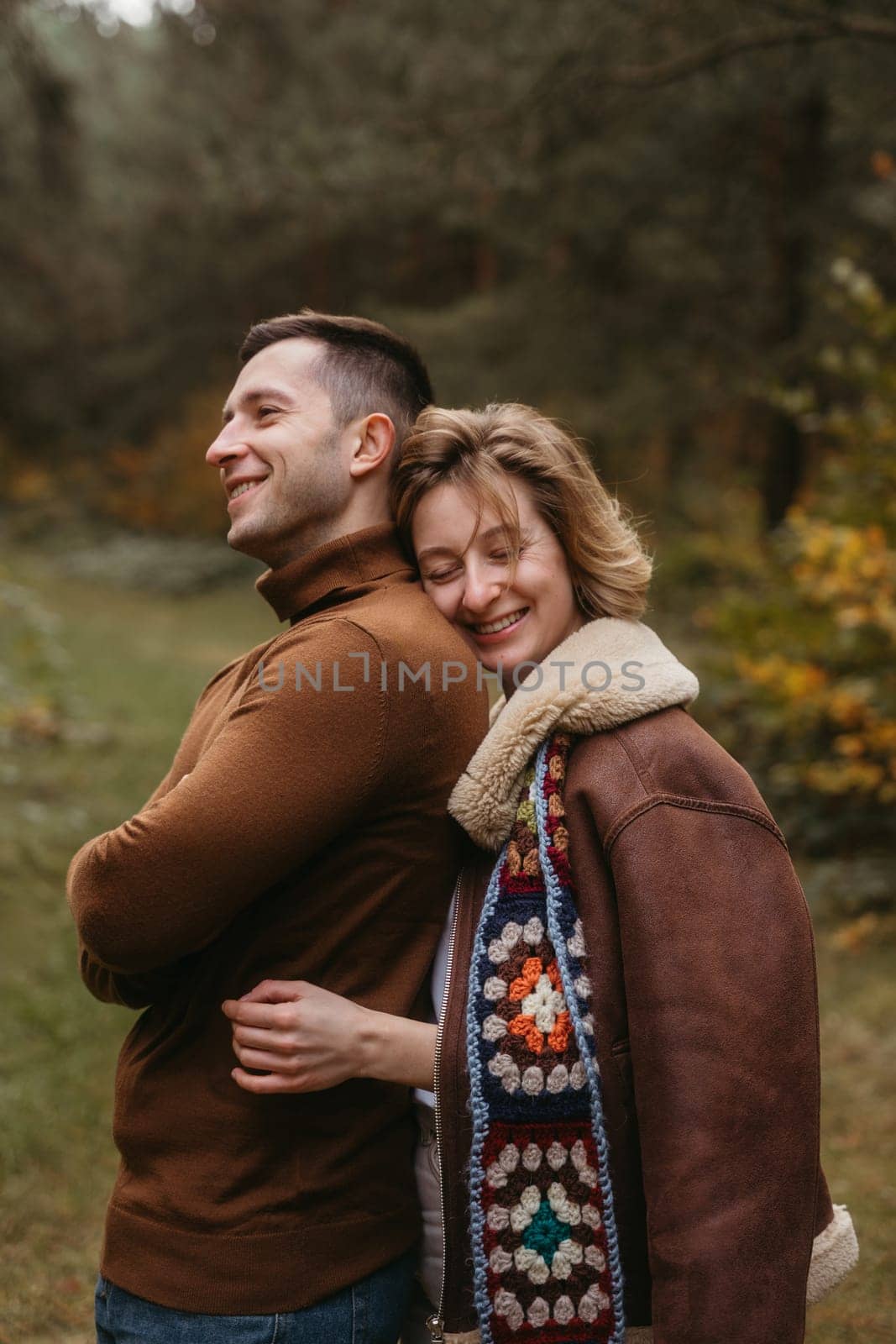 Smiling caucasian woman hugs man from behind, happy couple spending time in autumn park outdoors