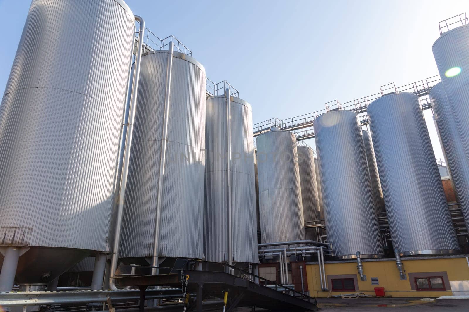 Brewery silos or tanks typically use for storing barley or fermented beer. Outdoor brewery equipment with stainless steel tanks and pipes.