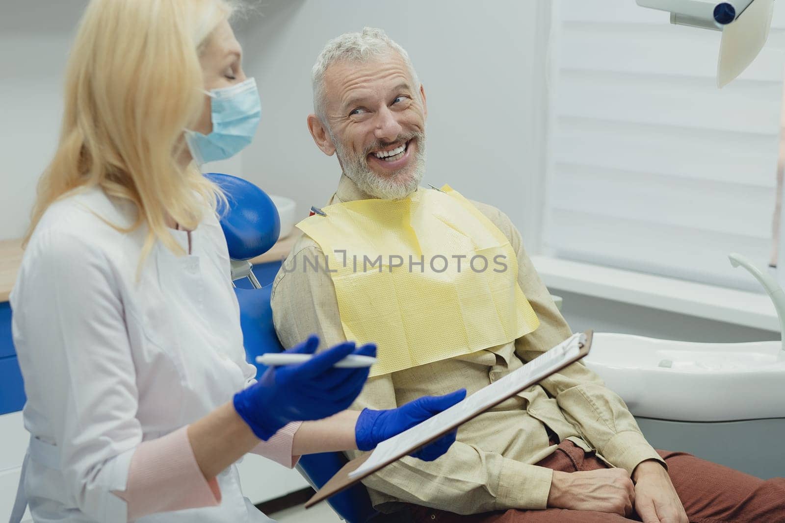 Dental doctor treating a male patient in hospital. by Сookiestock