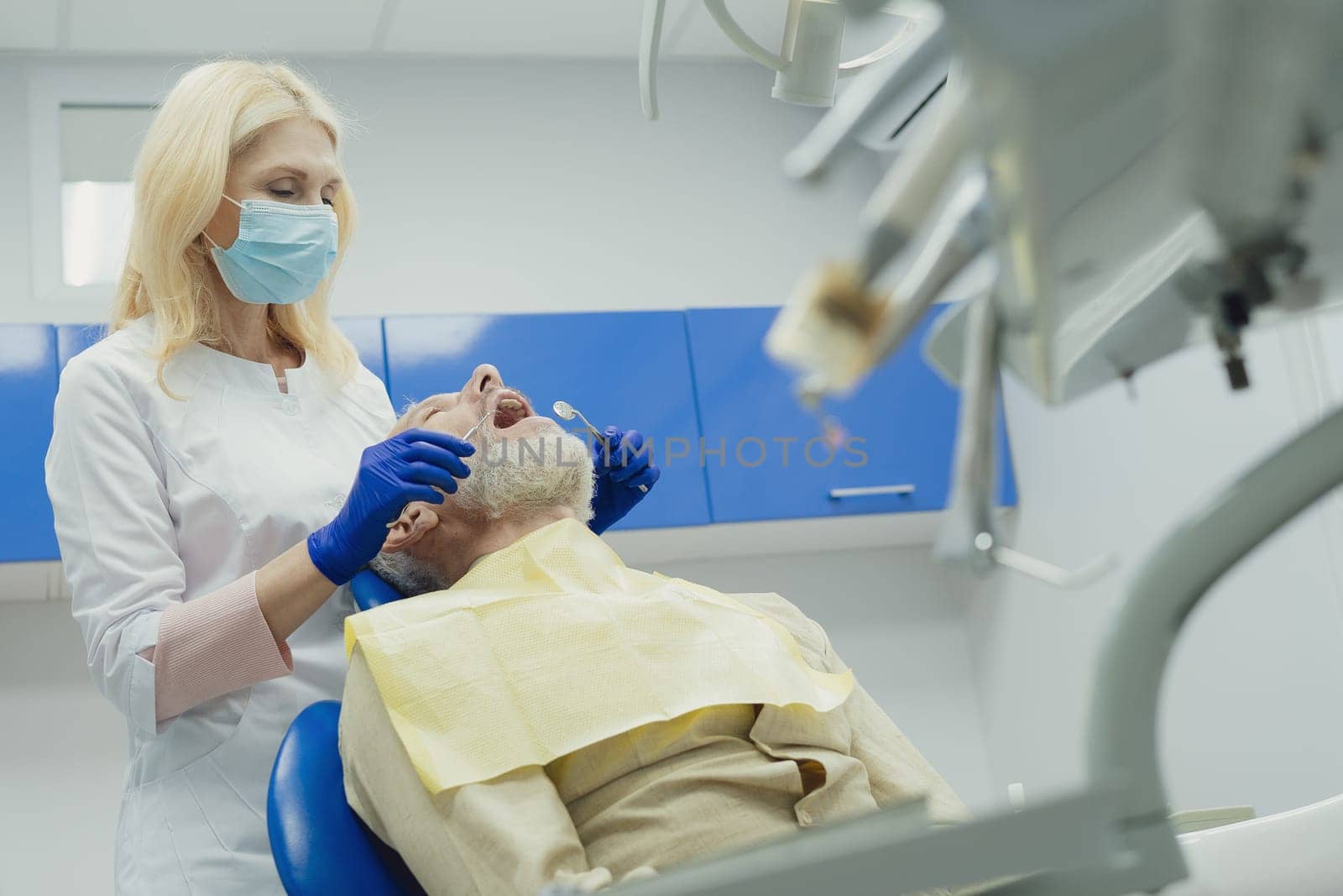 Dental doctor treating a male patient in hospital. by Сookiestock