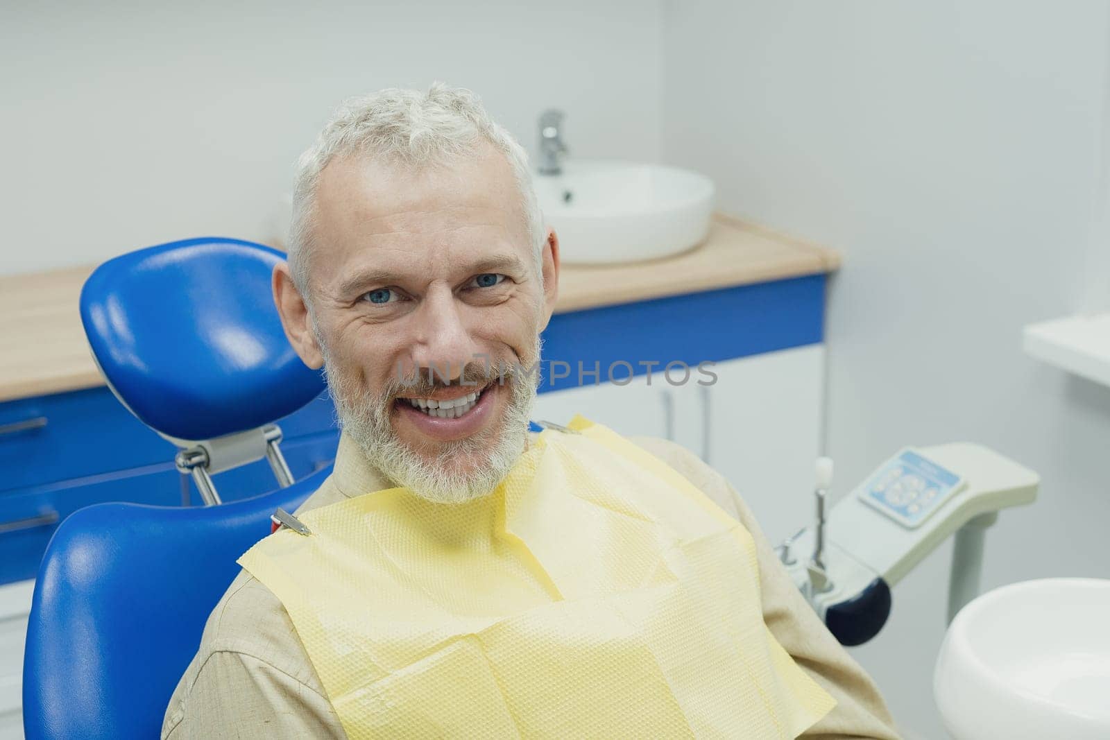 Dental doctor treating a male patient in hospital. by Сookiestock