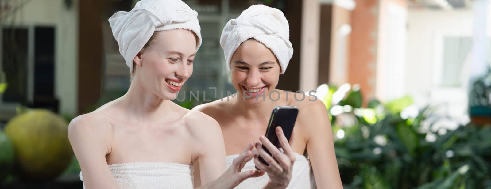 Couple of young beautiful women with beautiful skin in white towel taking a photo together at outdoor surrounded by peaceful natural environment. Beauty and healthy spa concept. Tranquility.