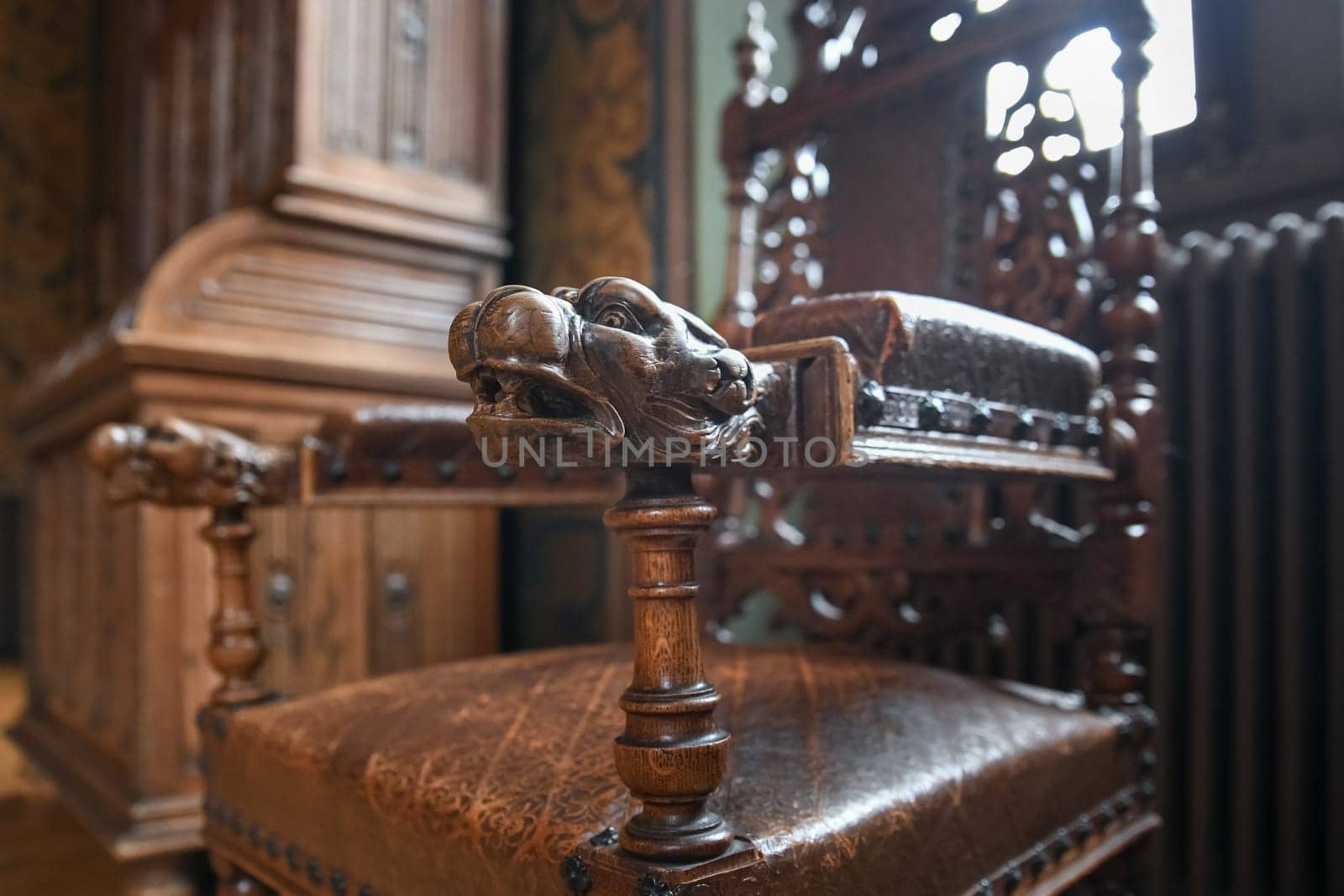 A wooden Renaissance armchair with a lion's head.