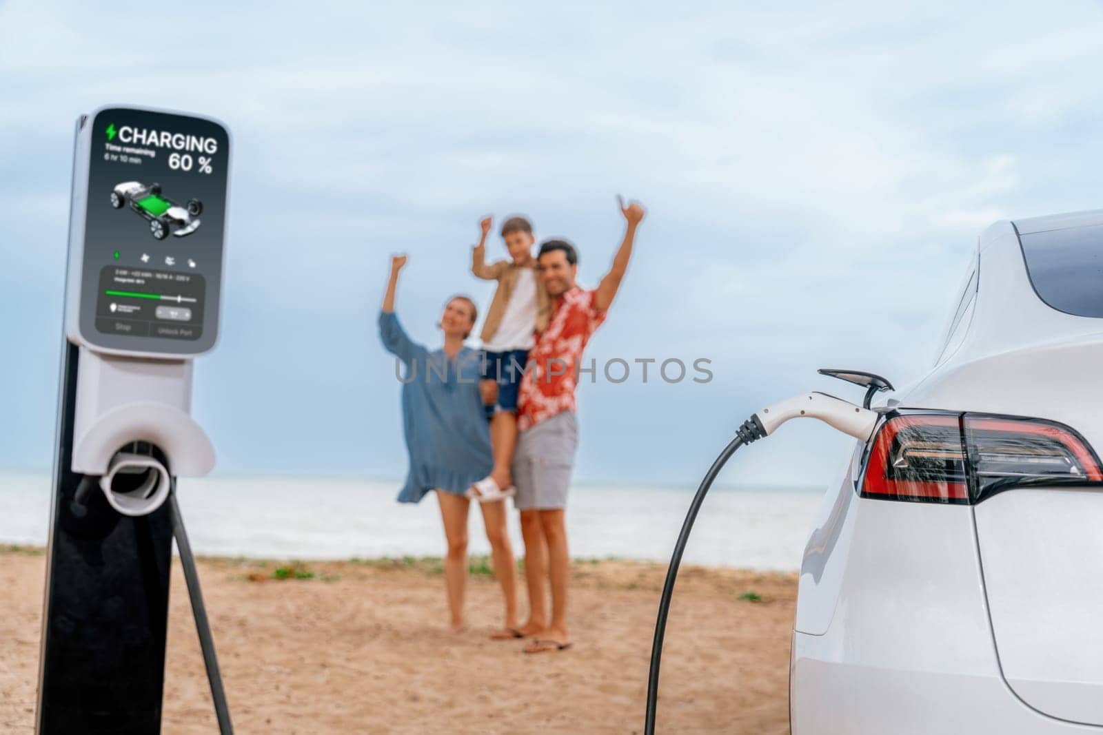 Alternative family vacation trip traveling by the beach with electric car recharging battery from EV charging station with blurred cheerful and happy family enjoying the seascape background. Perpetual