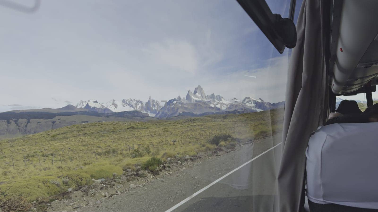 Wide-angle mountain view through a bus window while traveling.