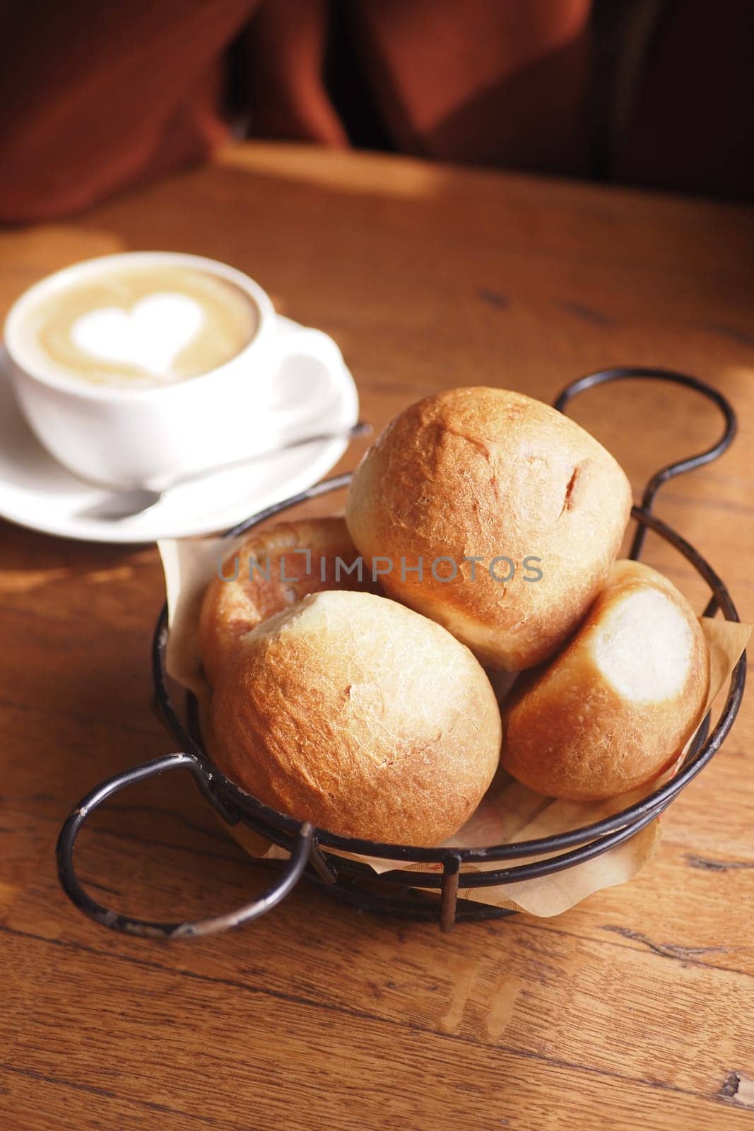 Three bread rolls rest in a black bowl on the table.