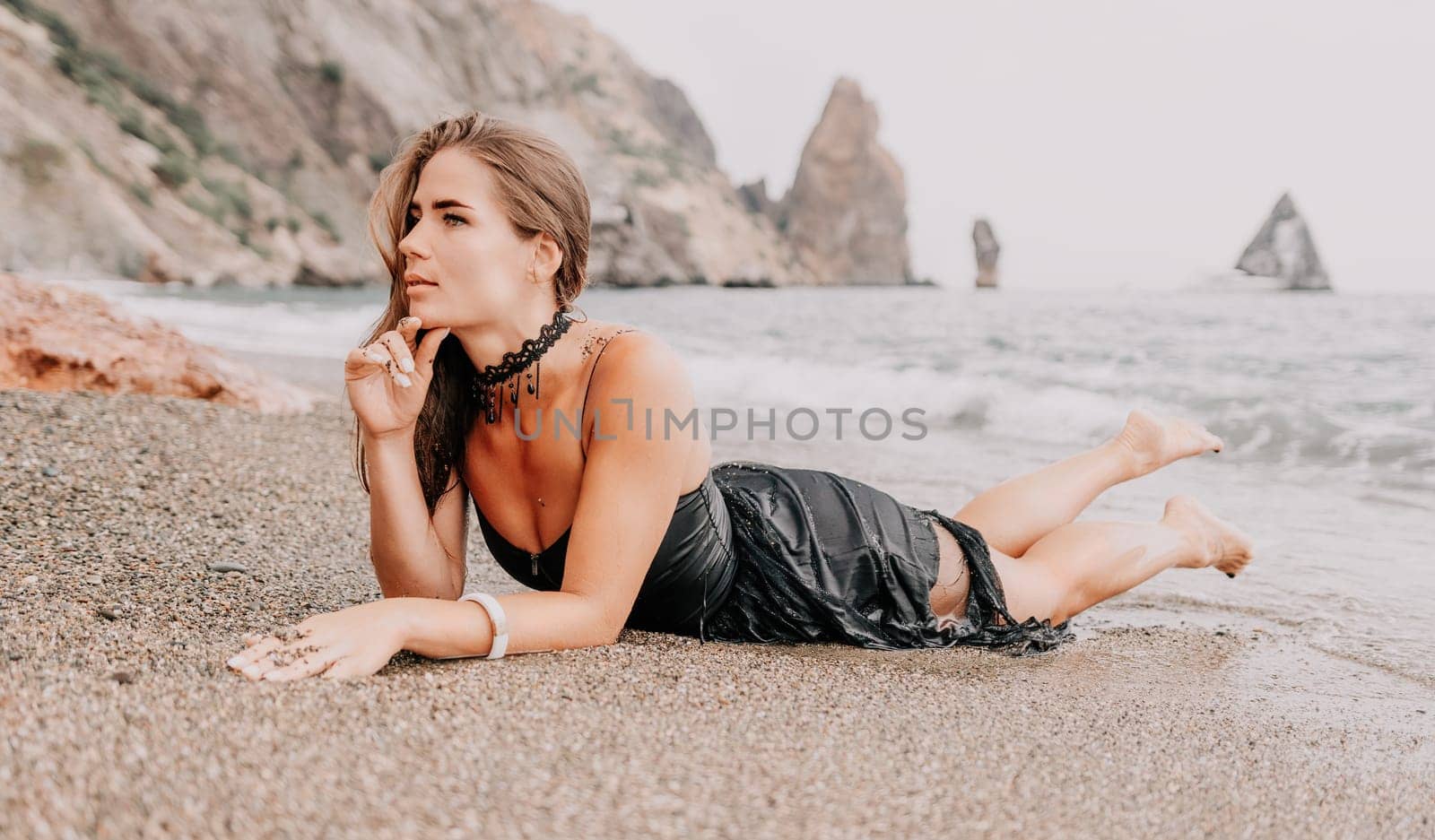 Woman travel sea. Young Happy woman in a long red dress posing on a beach near the sea on background of volcanic rocks, like in Iceland, sharing travel adventure journey