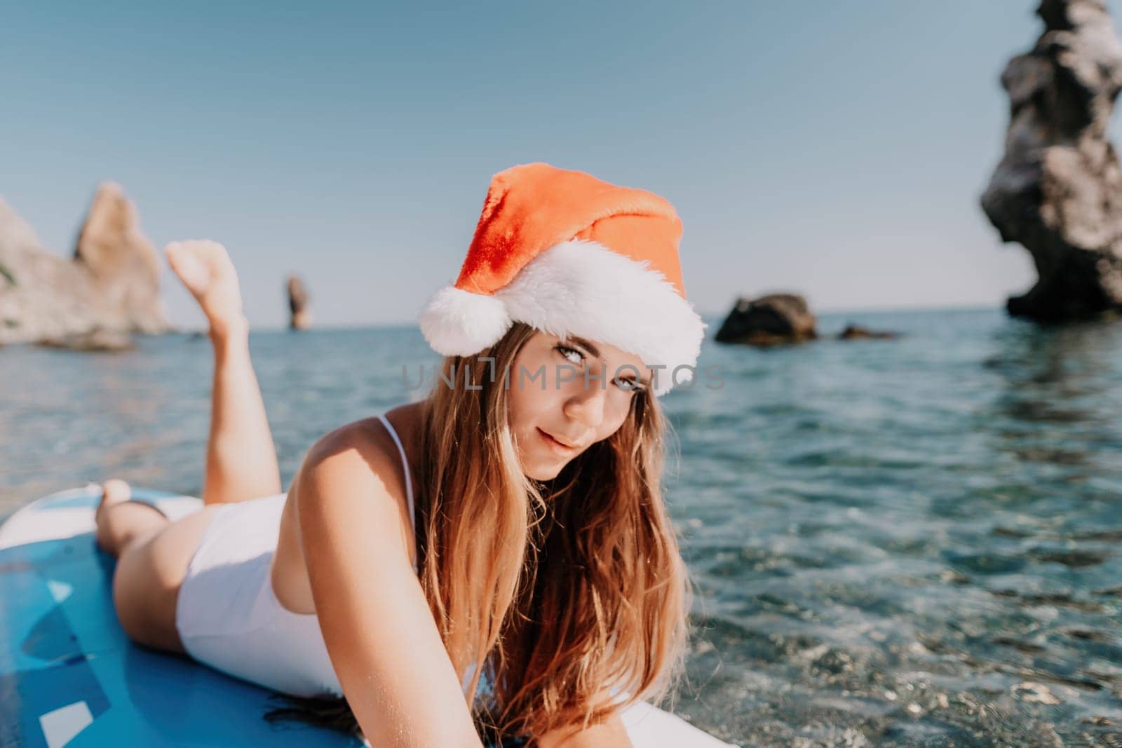 Close up shot of happy young caucasian woman looking at camera and smiling. Cute woman portrait in bikini posing on a volcanic rock high above the sea