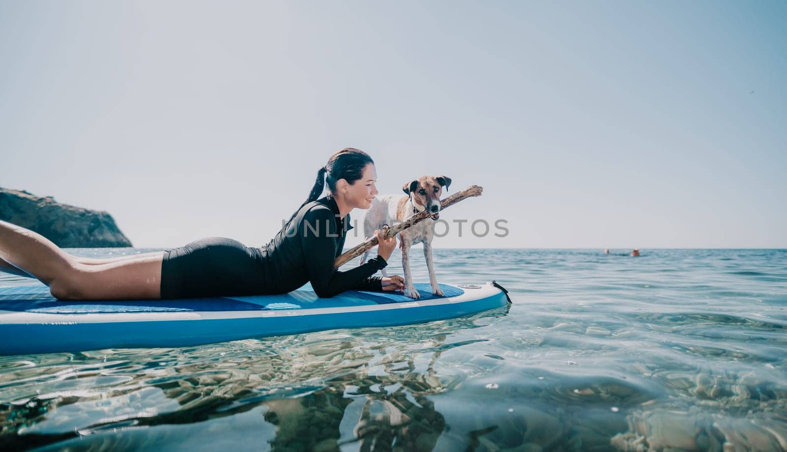 Sea woman sup. A happy positive woman in hat with family relaxing in sea, aerial back view of family on SUP board floating on calm water. Active lifestyle at sea. Summer vacation. Slow motion