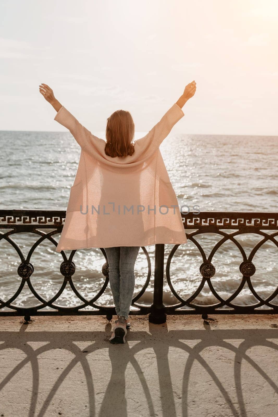 Woman travel sea. Young Happy woman in a long red dress posing on a beach near the sea on background of volcanic rocks, like in Iceland, sharing travel adventure journey