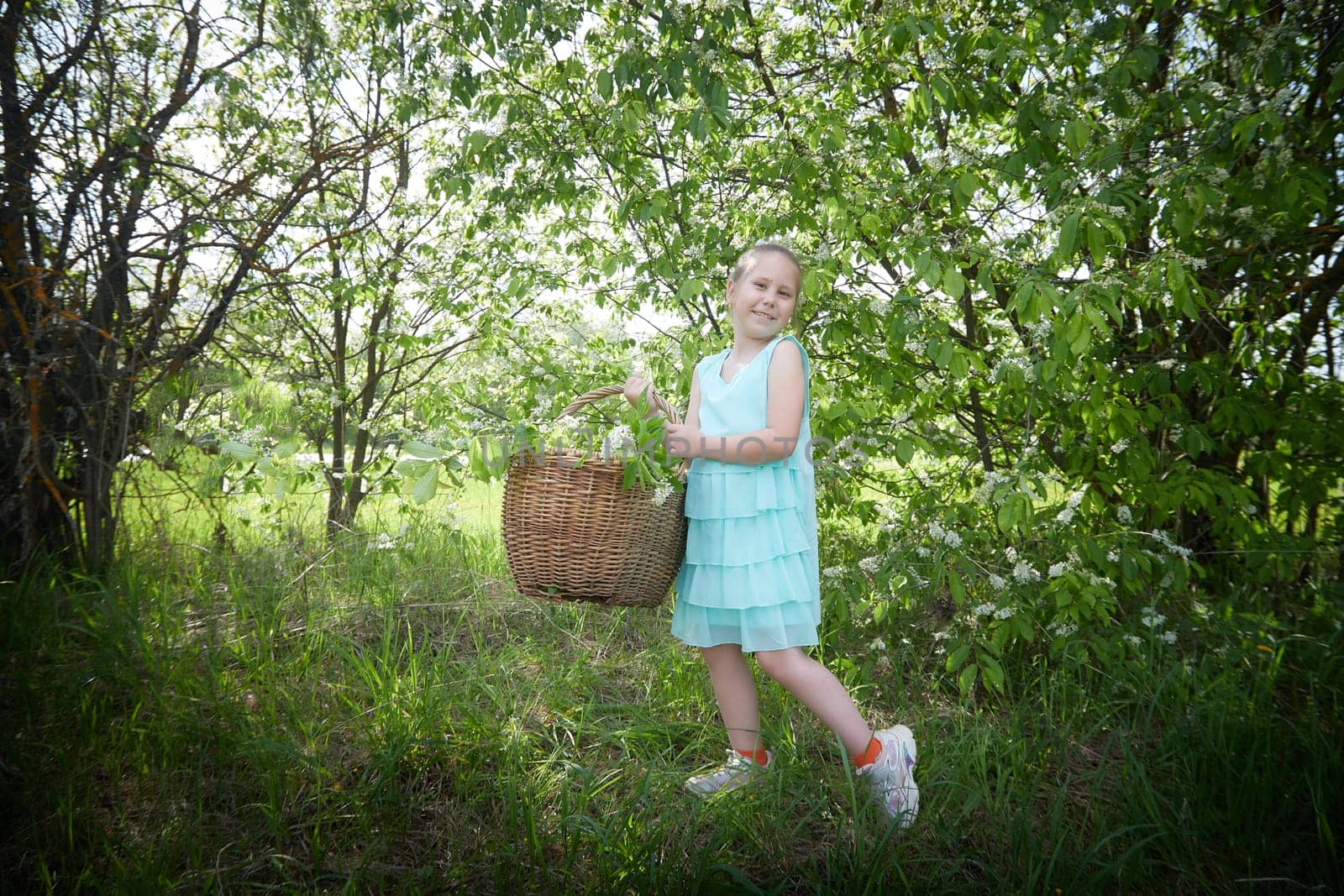 Little Happy Smiling Child Girl in blue dress on nature near greenery. SummerTime, Nature, Lifestyle and Country life