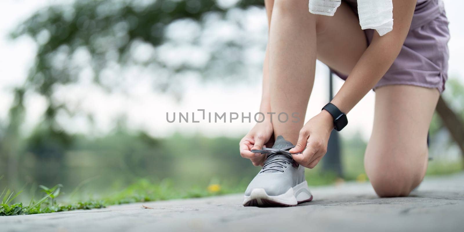 Woman tying shoe laces. Closeup of female sport fitness runner getting ready for jogging outdoors on park.