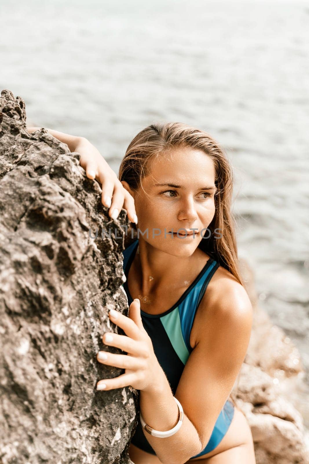 Woman beach vacation photo. A happy tourist in a blue bikini enjoying the scenic view of the sea and volcanic mountains while taking pictures to capture the memories of her travel adventure