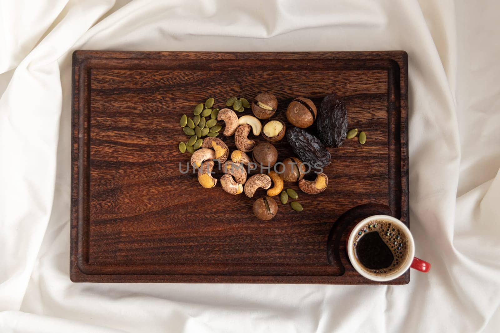 Wooden tray with various nuts on clean white bedding. Good morning concept