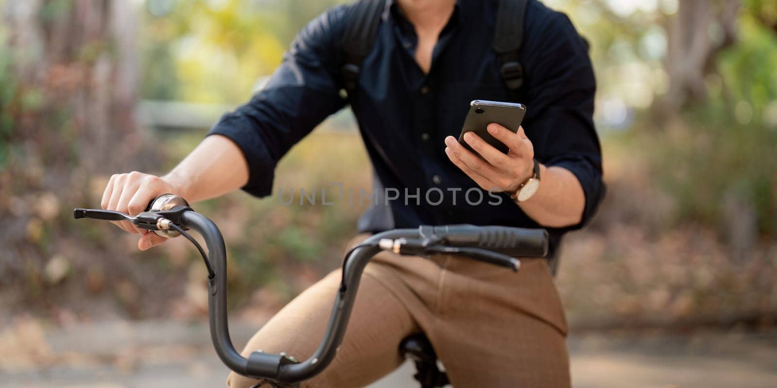 Businessman with bicycle using smartphone outside the office building. man commuting on bike go to work. Eco friendly vehicle, sustainable lifestyle concept.