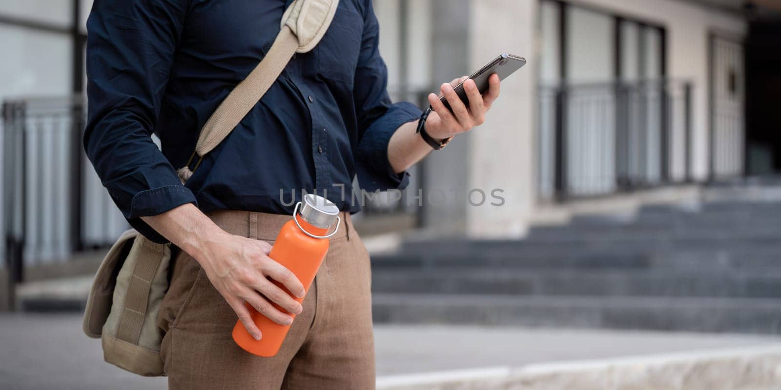 Businessman walking to work while to hold reusable eco friendly ecological cup in the city.