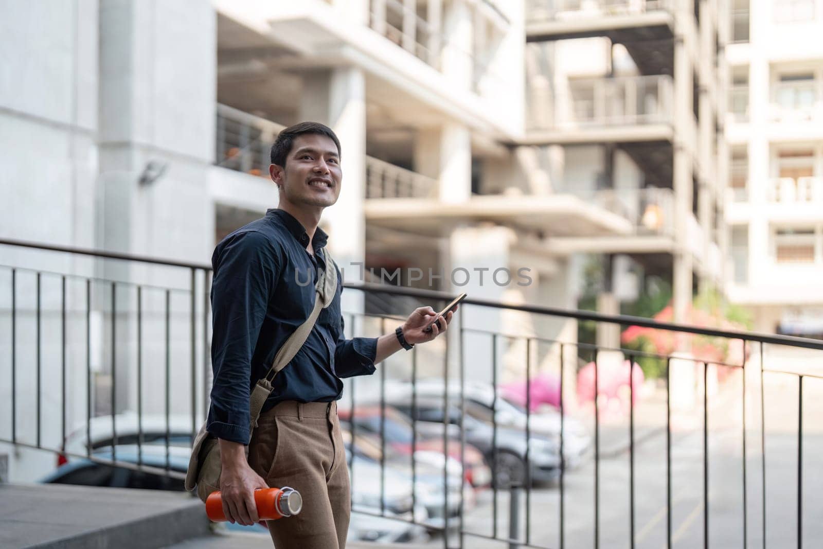Smiling asian businessman walking to work while to hold reusable eco friendly ecological cup in the city by nateemee