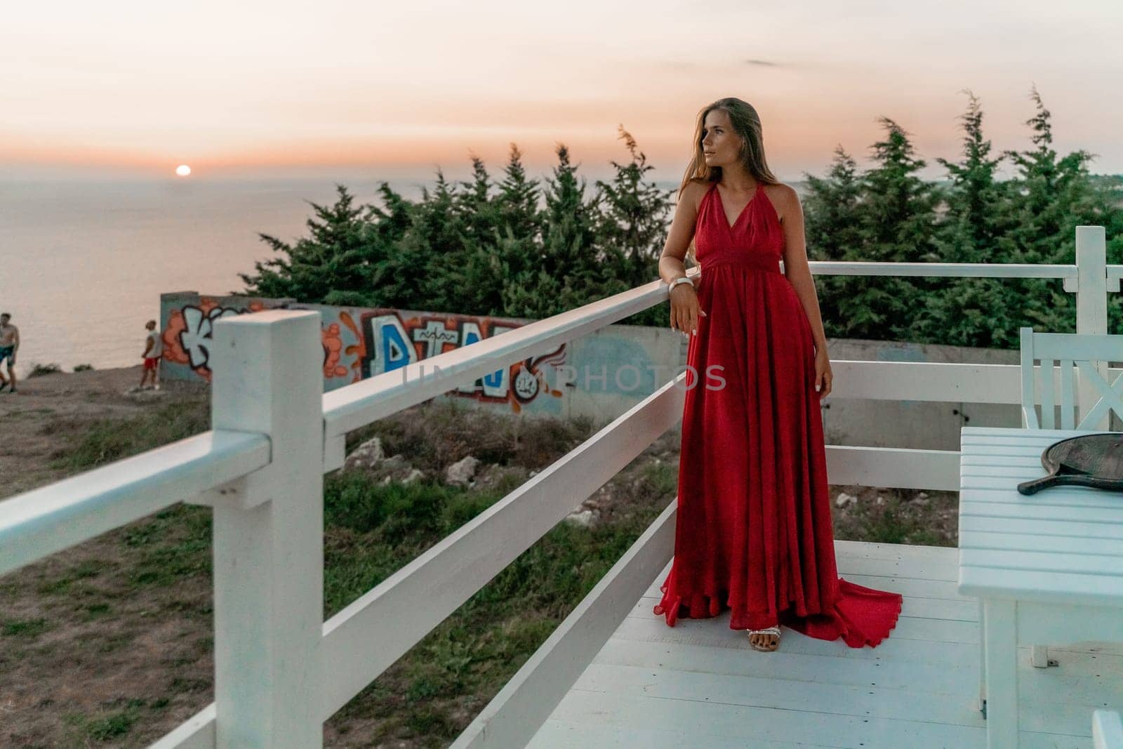 Woman sunset sea red dress, portrait happy beautiful sensual woman in a red long dress posing above the sea on sunset