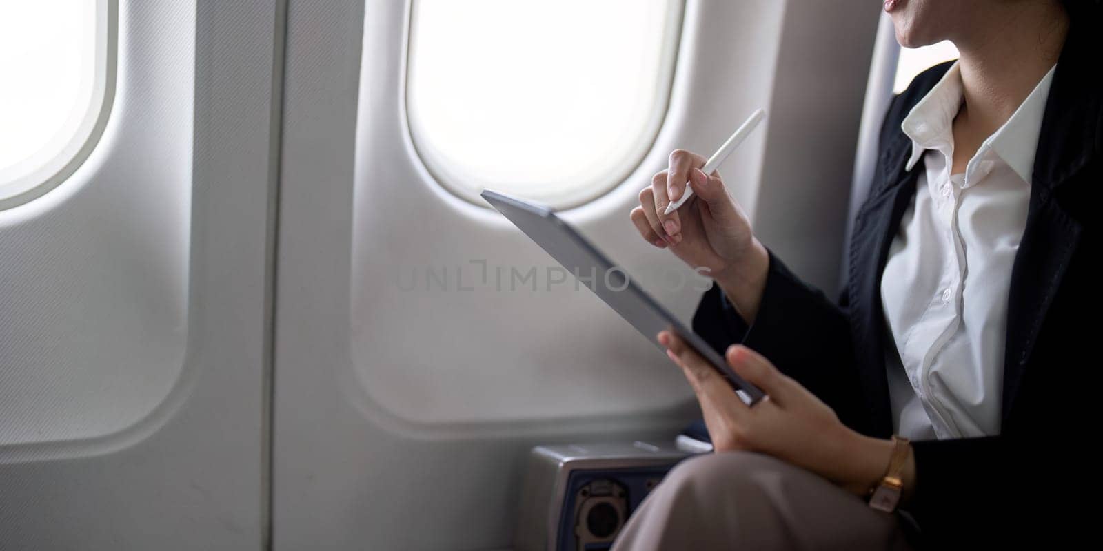 Young asian business woman sits in airplane cabin plane and working from anywhere. Flying at first class.