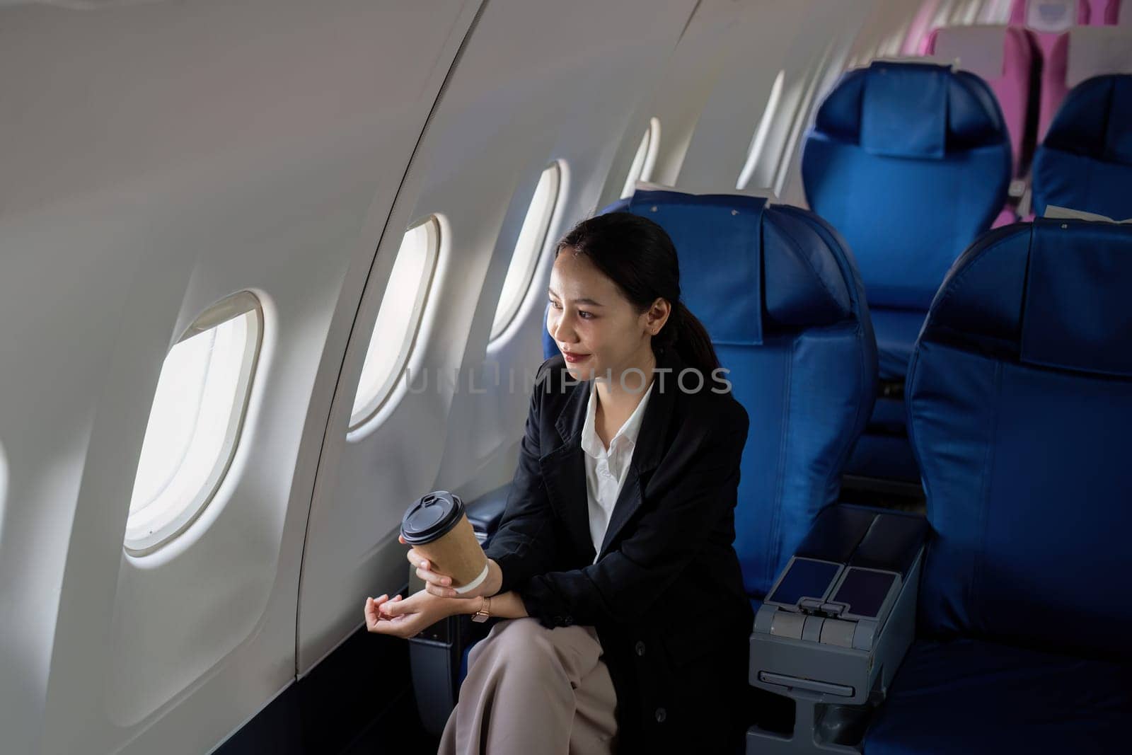 Successful asian businesswoman or female entrepreneur in a plane sits in a business class seat by nateemee