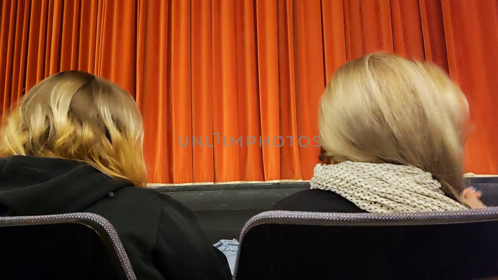 theater, red curtain, two women's heads, spectators. High quality photo