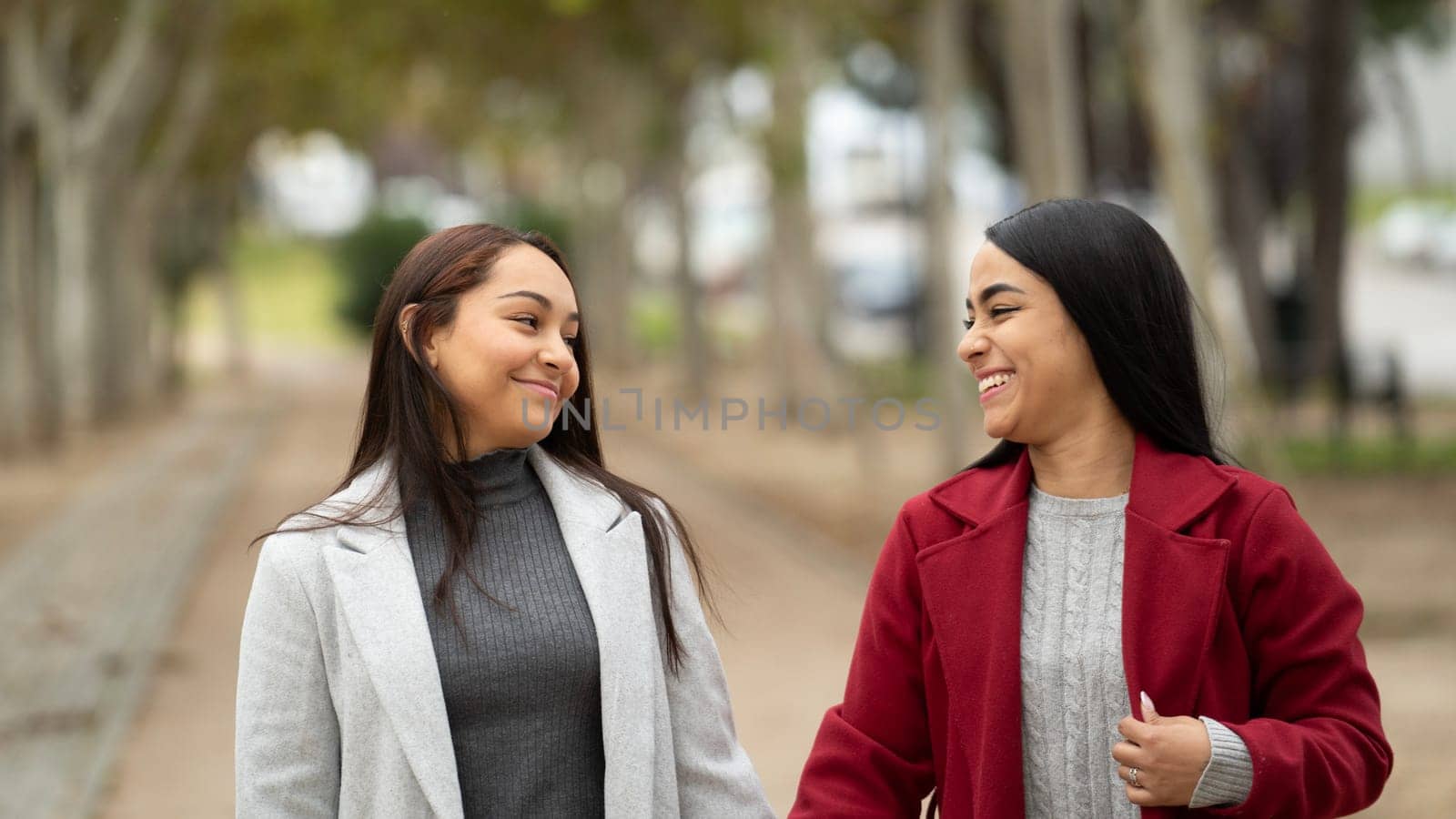 Lesbian couple smiling and looking at each other in a park by papatonic