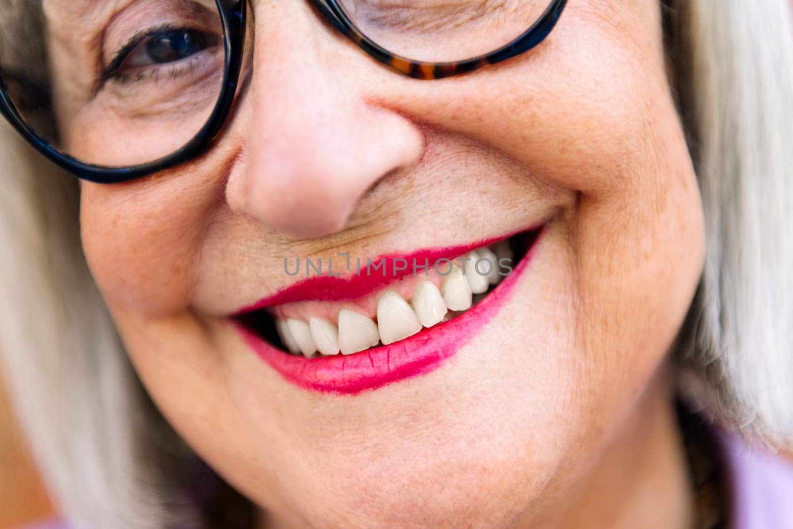 close up detail of toothy smile of a beautiful senior woman, concept of elderly people happiness and active lifestyle