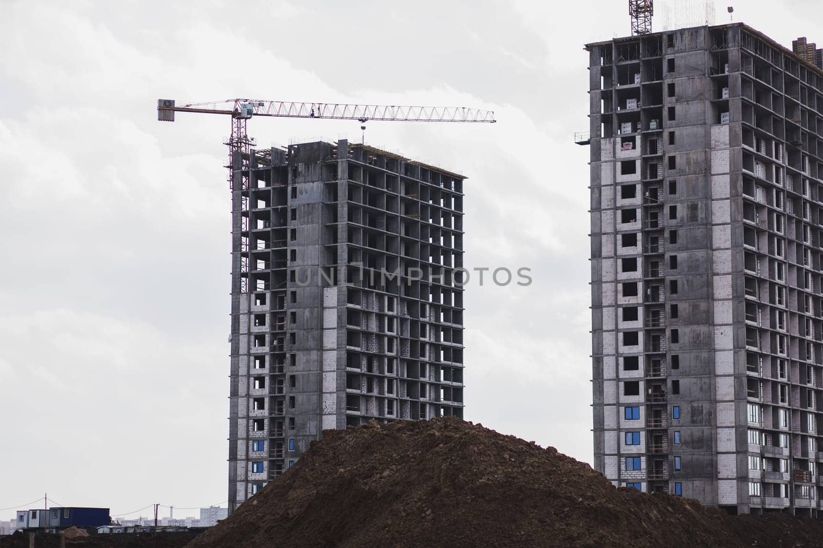 building cranes at the background of a multi-storey building under construction. New houses for families