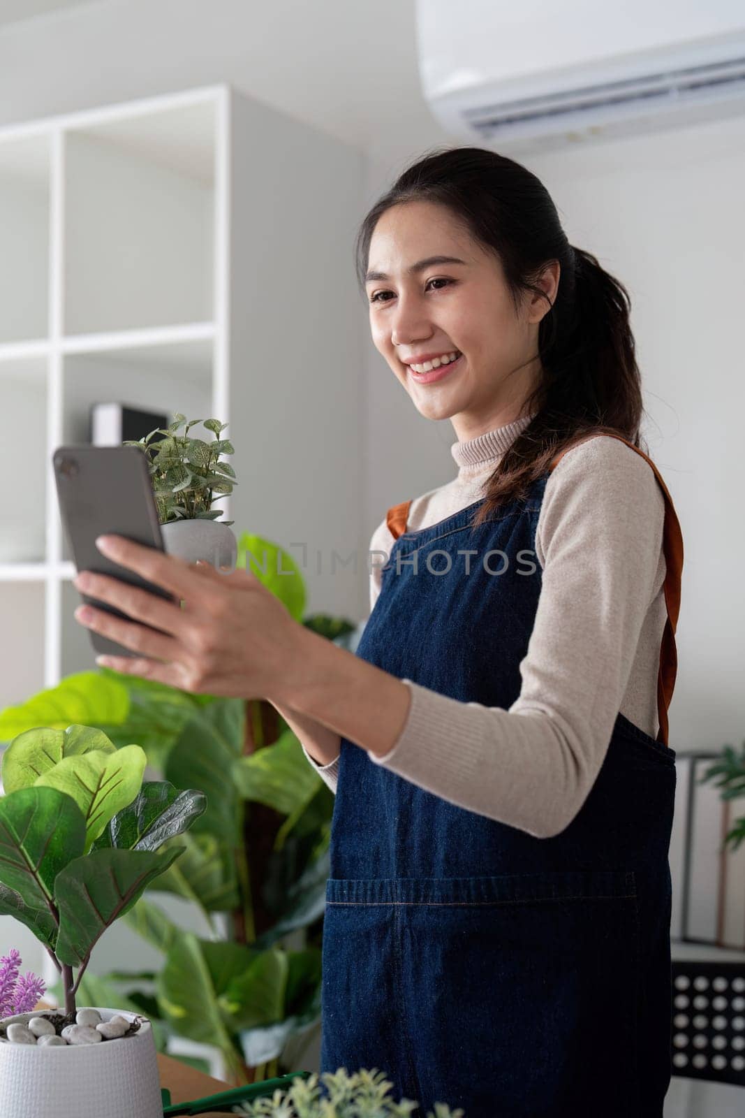The concept of eco friendly housing, plant care and gardening. Relax home gardening. Gardener woman asian take a selfie with plant. Smiling woman takes care of plant by nateemee