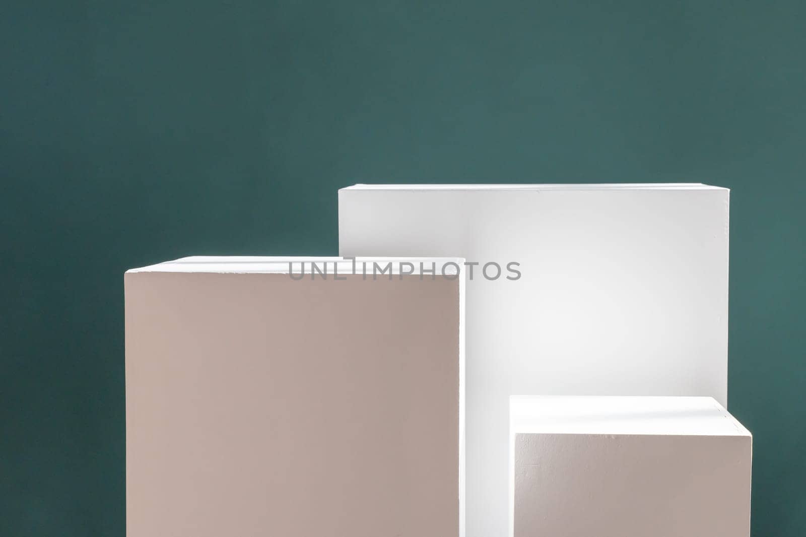 Three white rectangular boxes against a green wall with shadows. Product photography background. Pedestal for cosmetic product and packaging mockups display presentation