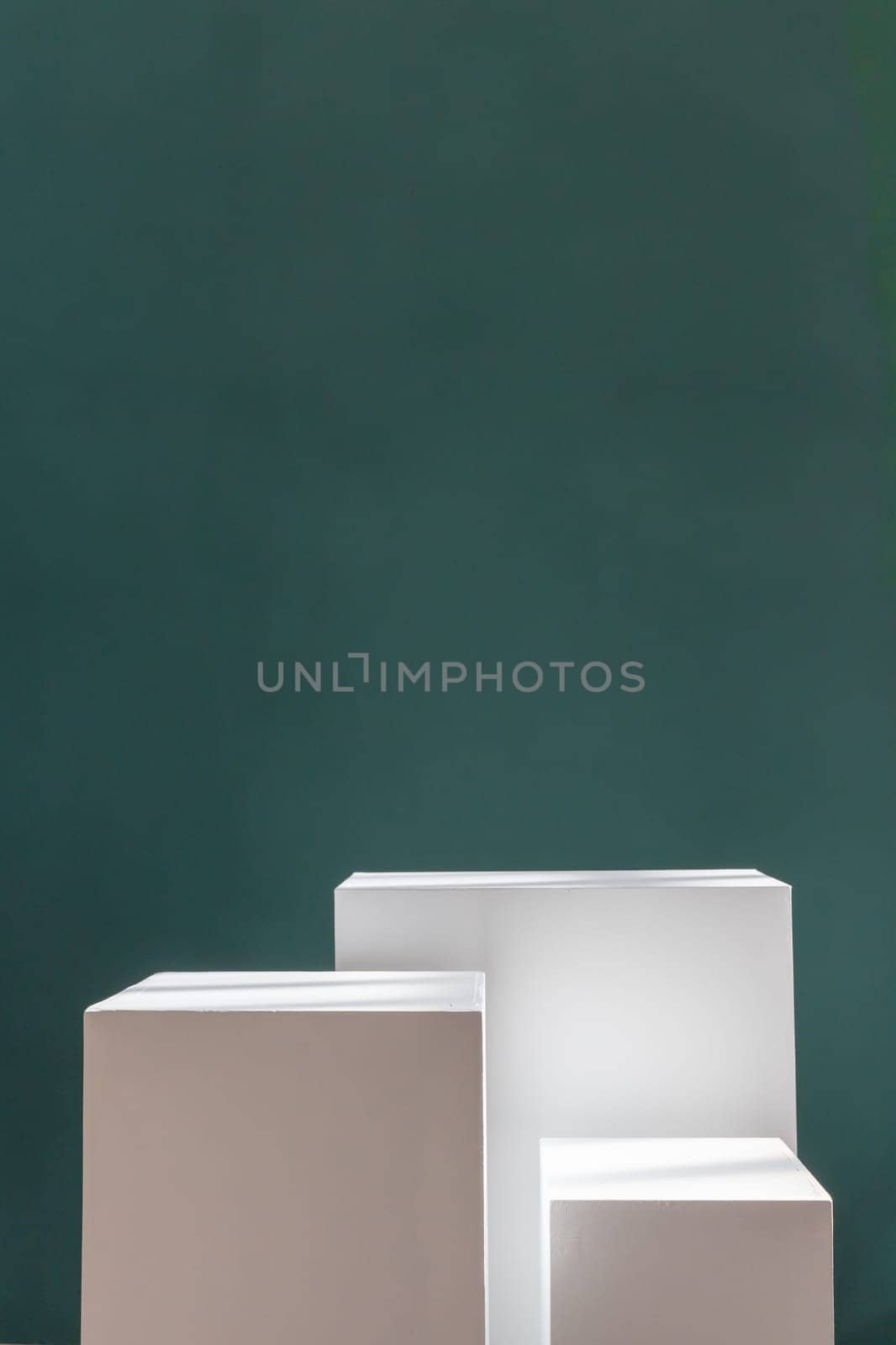 Three white rectangular boxes against a green wall. Product photography background. Pedestal for cosmetic product and packaging mockups display presentation