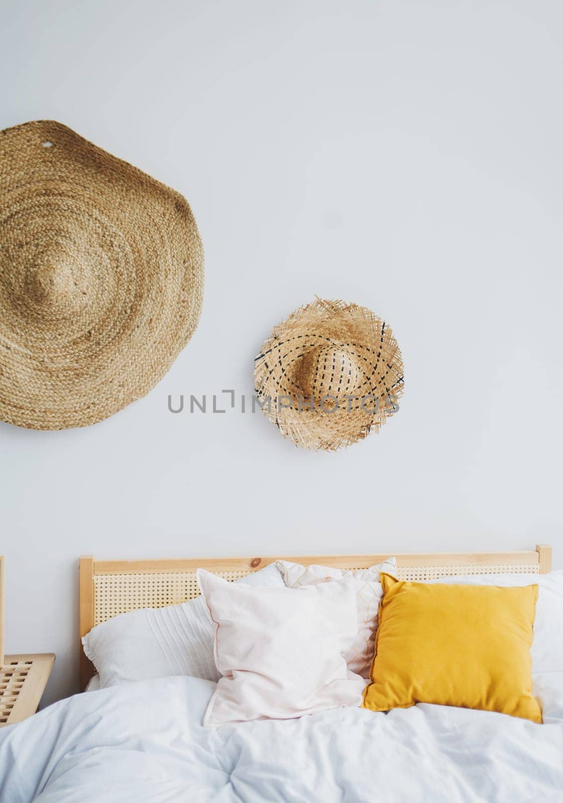 the interior of the modern bedroom with bright pillows and old straw hats