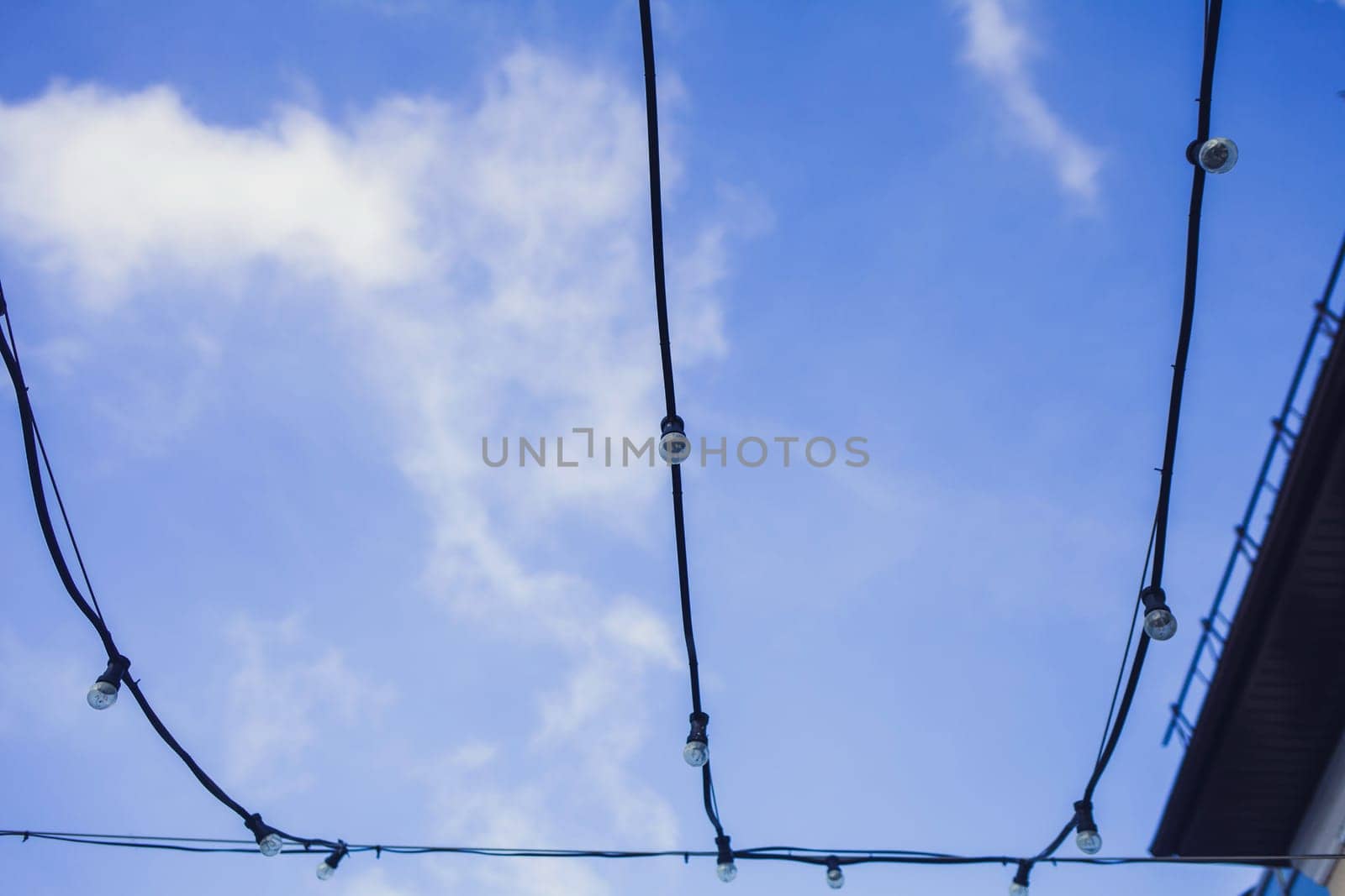 Several electric glass lamps in a garland against the evening blue sky.