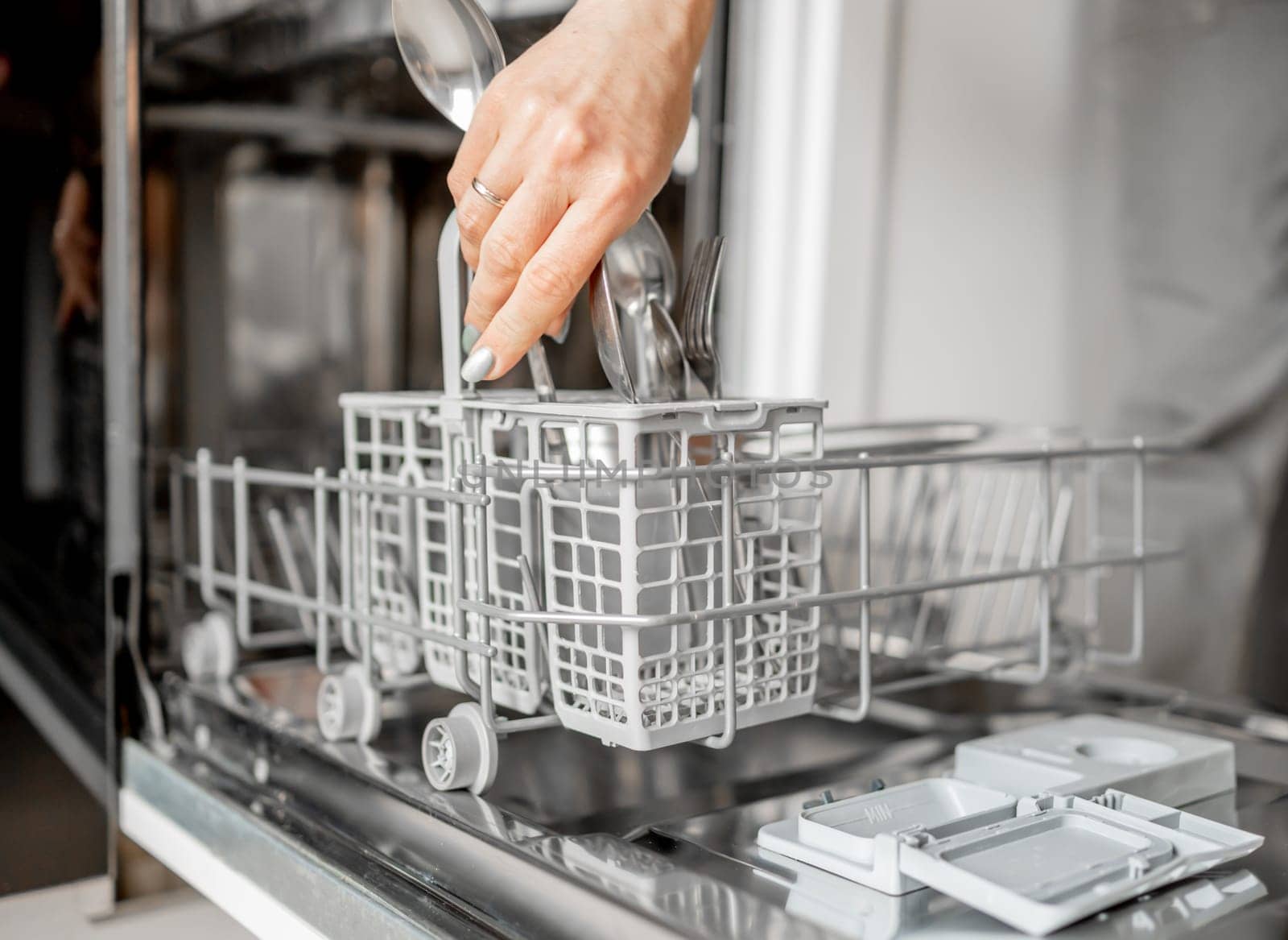 Young Woman Is Loading Spoons Into Dishwasher In Close-Up View