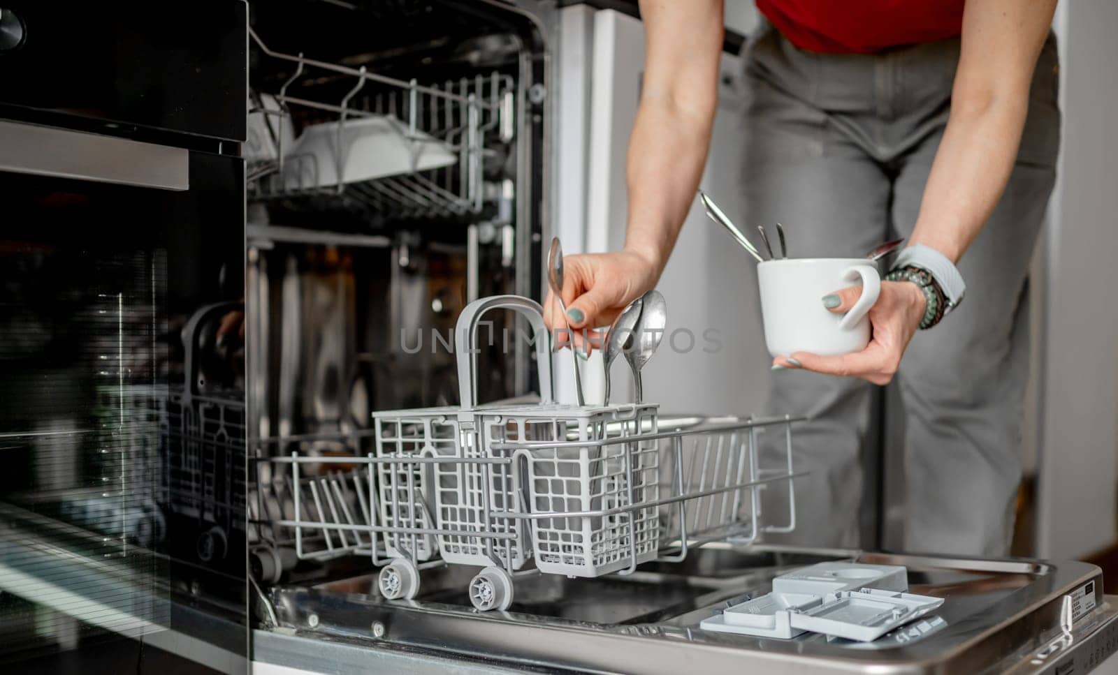 Young Woman Is Loading Spoons Into Dishwasher In Close-Up View