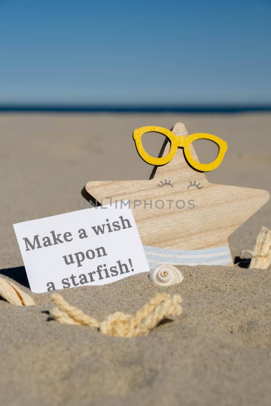 MAKE A WISH UPON A STARFISH text on paper greeting card on background of funny starfish in glasses summer vacation decor. Sandy beach sun coast. Holiday concept postcard. Getting away Travel Business concept