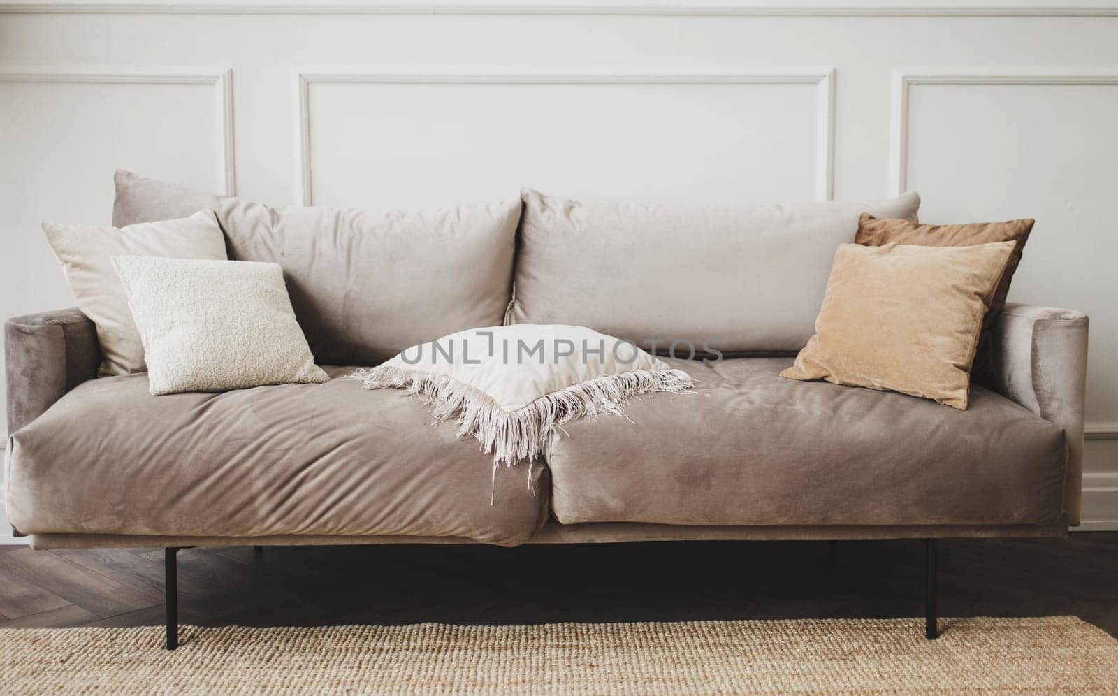 gray sofa with pillows against a white, empty wall in a simple living room interior