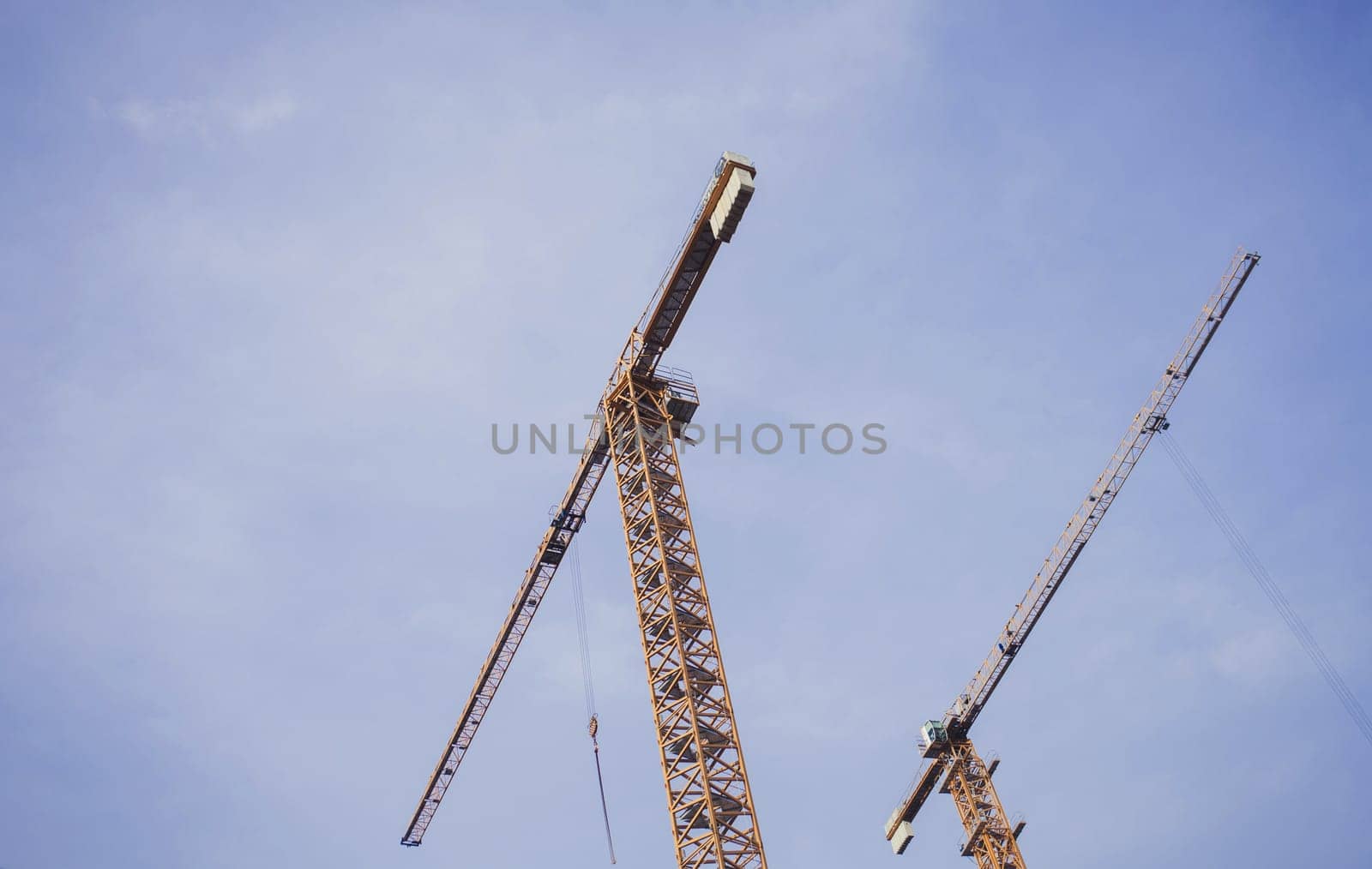 two construction cranes on blue sky background