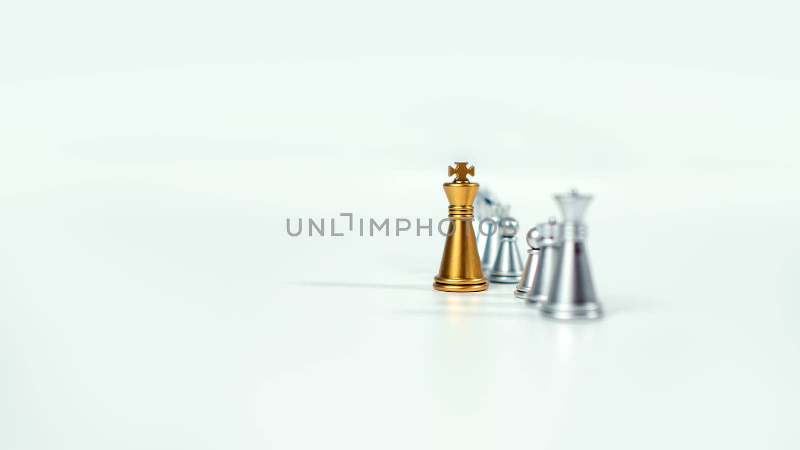 Golden king chess on the board in front of silver chess pieces on white background with copy space, Leadership, fighter, business leadership, competition, confrontation, and business strategy concept.