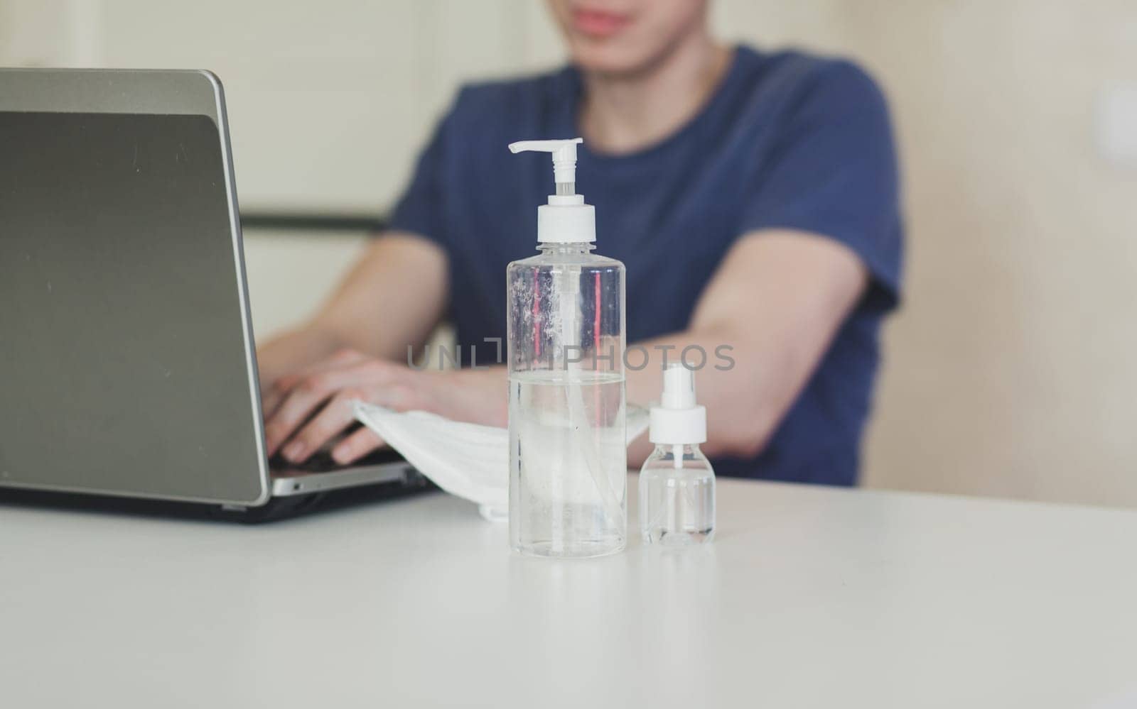 Man working from home at notebook. Quarantine for coronavirus. Working from home. Cleaning her hands with sanitizer gel.