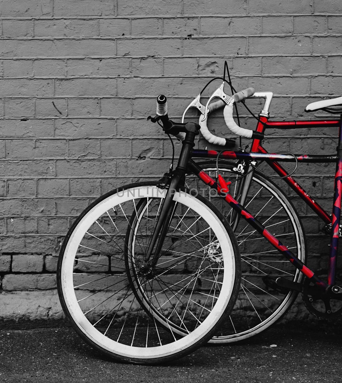 two vintage bicycles parking against red brick wall