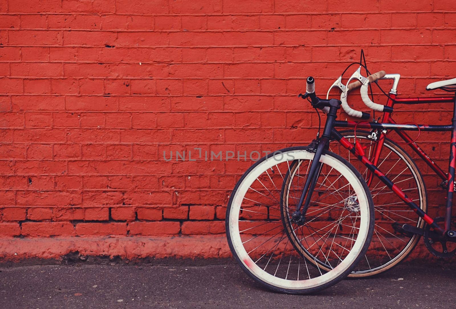 two vintage bicycles parking against red brick wall. copy space