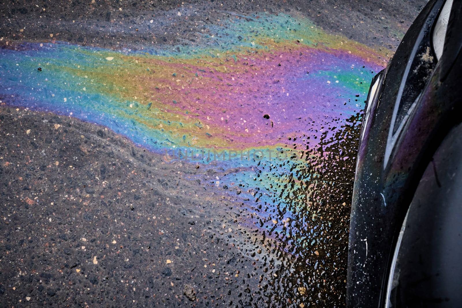 Gasoline and oil spill on wet asphalt in a parking lot near a hypermarket.