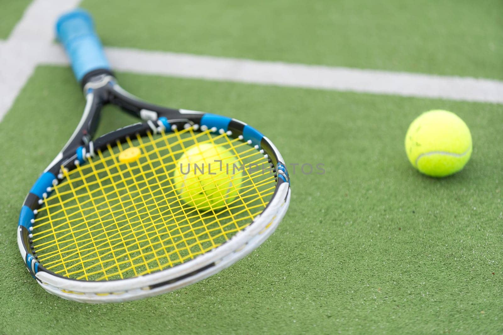 Tennis racket and tennis ball besides the net on outdoor tennis court. High quality photo