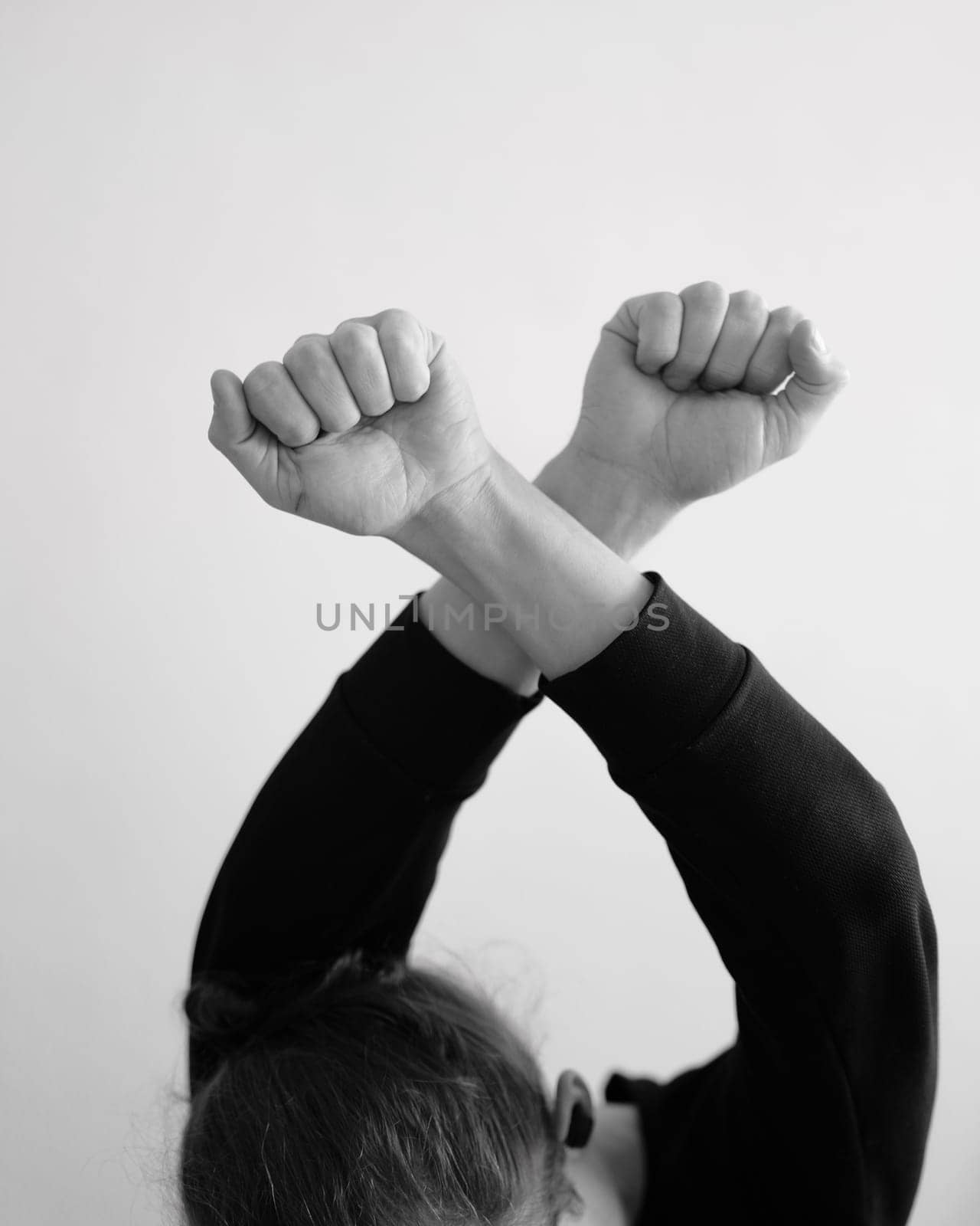 A person holding crossed hands above the head. X symbol using the hands in black and white.